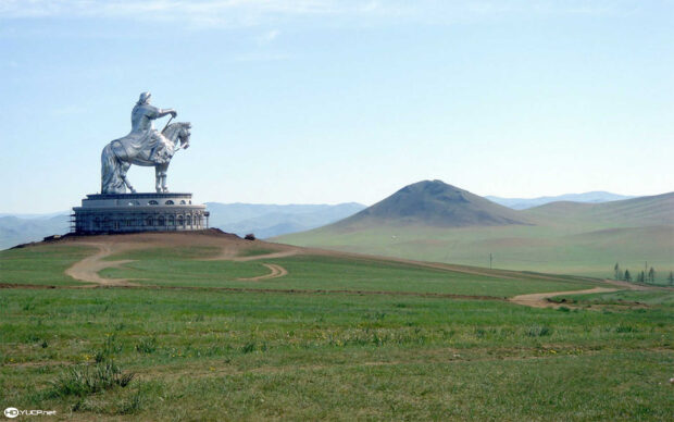 Statue of Genghis Khan on horseback in the Mongolian steppe with hills in the background