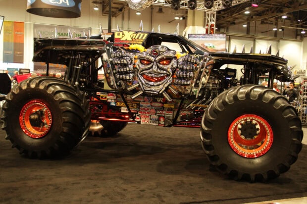 A monster truck with detailed chrome decorations and large tires displayed at an indoor event
