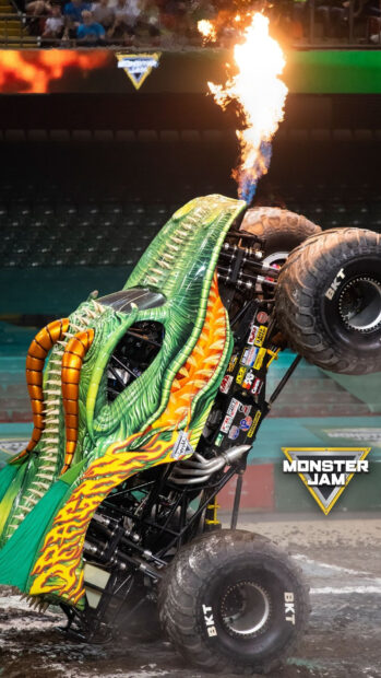Green monster truck breathing fire during a monster truck event