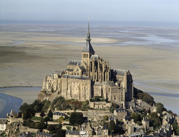 Mont Saint Michel historical landmark surrounded by tidal flats under a clear sky