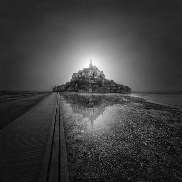 Mont Saint Michel as seen from the wooden pathway with its reflection on the water at low tide