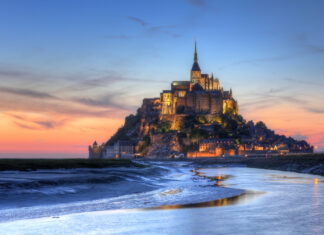 Mont Saint Michel sunset view with illuminated historic buildings on rocky island