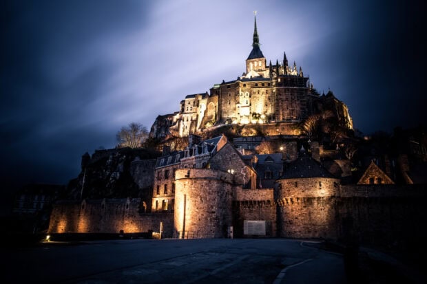 Illuminated Mont Saint Michel during night showcasing historic architecture and surrounding walls