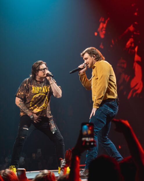 Morgan Wallen performing on stage with a fellow musician during a live concert show
