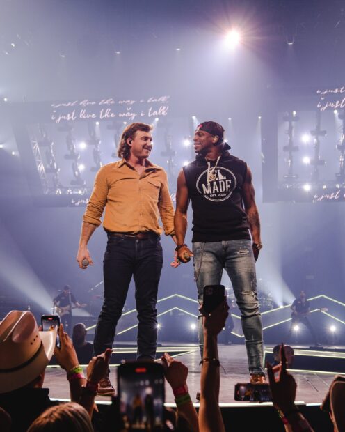 Two performers on stage during a Morgan Wallen concert crowd recording the show with phones