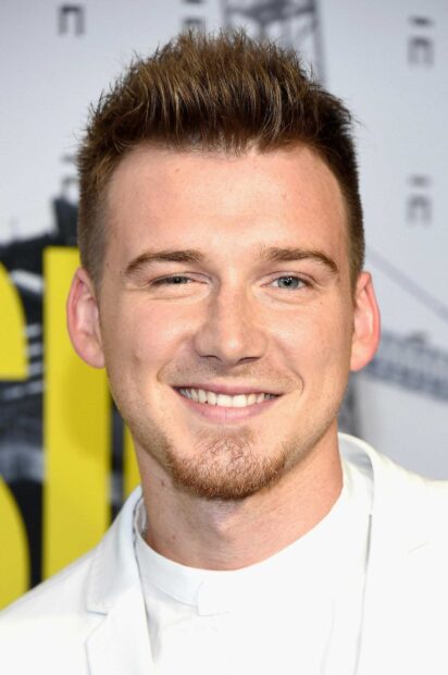 Close up of Morgan Wallen smiling with short hair and a light beard