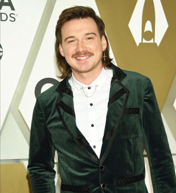Morgan Wallen wearing a green velvet jacket smiling at an awards event