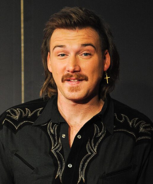 Morgan Wallen with mustache wearing embroidered black shirt and cross earring