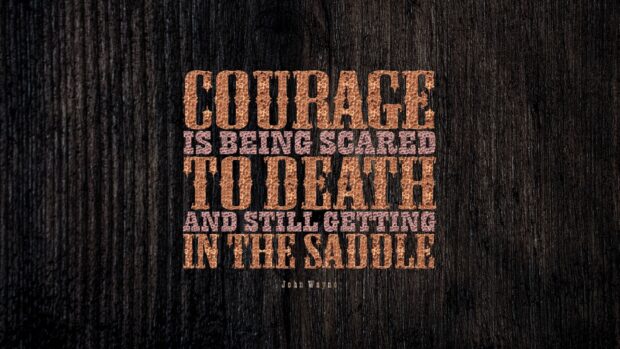 Courage is being scared to death and still getting in the saddle motivational quote on wooden texture background