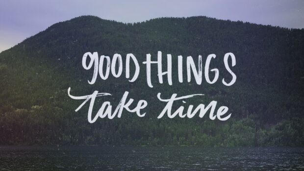 Good things take time motivational quote on forest and lake landscape
