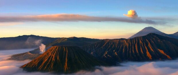 Volcanic landscape of Mount Bromo with smoke rising above the crater at sunrise