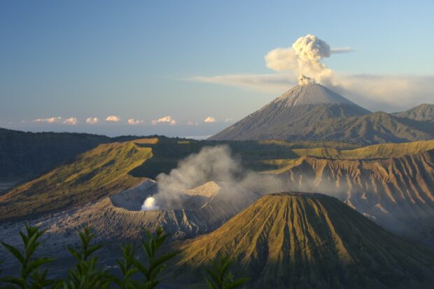Volcanic activity at Mount Bromo with smoke rising from the crater surrounded by rugged terrain