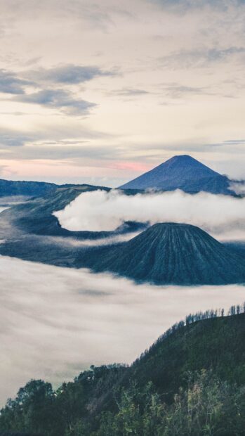 Misty morning view of Mount Bromo surrounded by clouds and hills