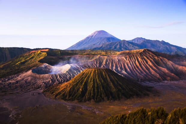 A breathtaking view of Mount Bromo volcano with surrounding mountains and smoke rising from the crater