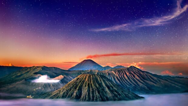 Mount Bromo volcano under the clear starry sky with smoke rising from the crater