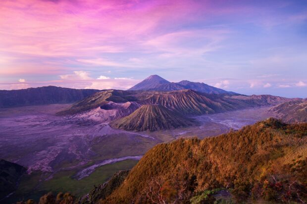 The panoramic view of Mount Bromo volcanic landscape during sunrise with purple sky