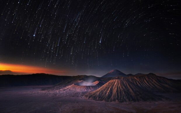 A stunning view of Mount Bromo under star trails in the night sky