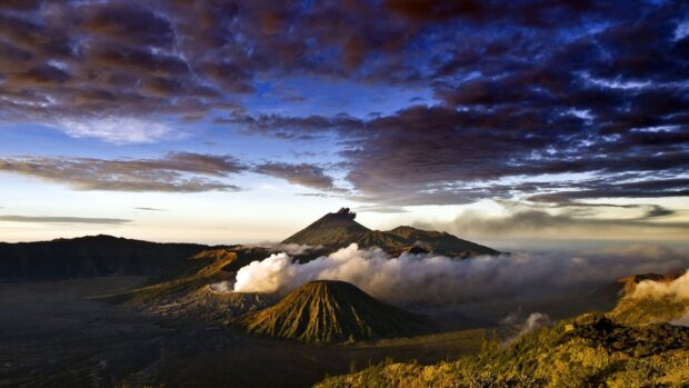 Mount Bromo volcano emitting smoke under a dramatic cloudy sky in a high quality landscape
