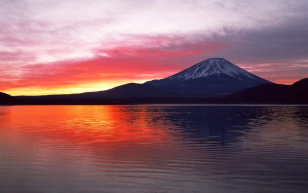 Mount Fuji with snow capped peak reflected in lake at vibrant sunset