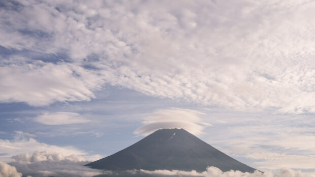Mount Fuji with unique cloud formations above the mountain peak and a partly cloudy sky