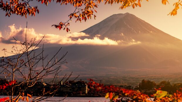 Mount Fuji mountain with autumn foliage and clouds over a lakeside town at sunset