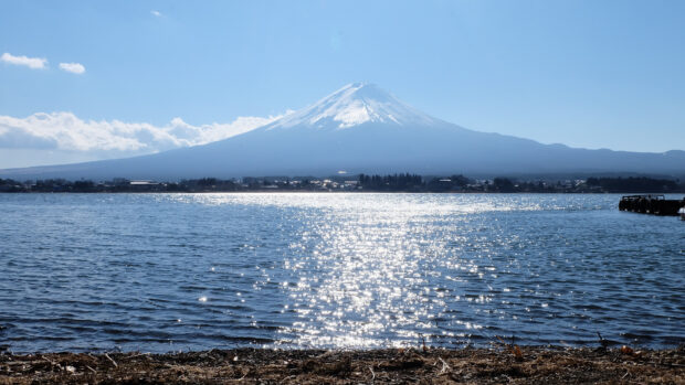 A clear view of Mount Fuji with sparkling water in the foreground and blue sky above