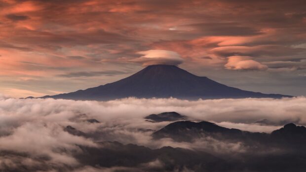 Mount Fuji surrounded by clouds at sunset with a lenticular cloud above the peak