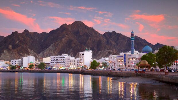 Evening view of Muscat Oman city with mountains and waterfront reflections
