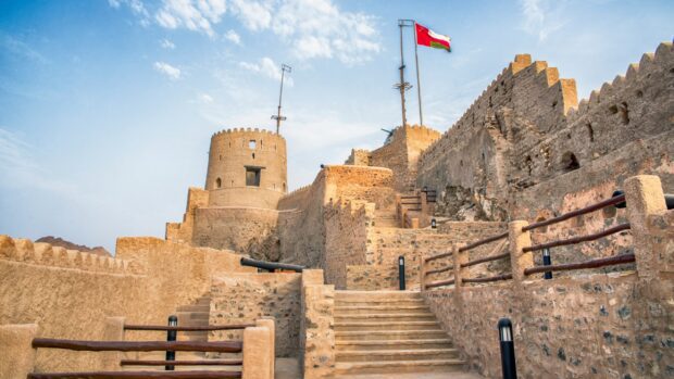 Historic castle in Muscat Oman with flag and stone walls visible on a clear day