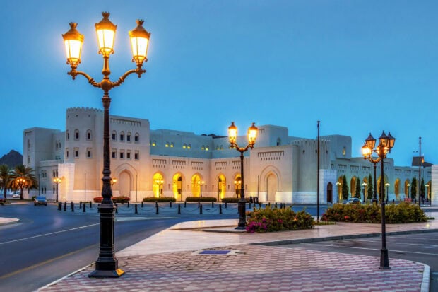 Historic architecture in Muscat Oman with illuminated street lamps during twilight