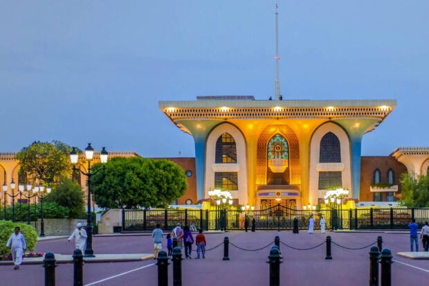 The illuminated royal palace with visitors in Muscat Oman during twilight