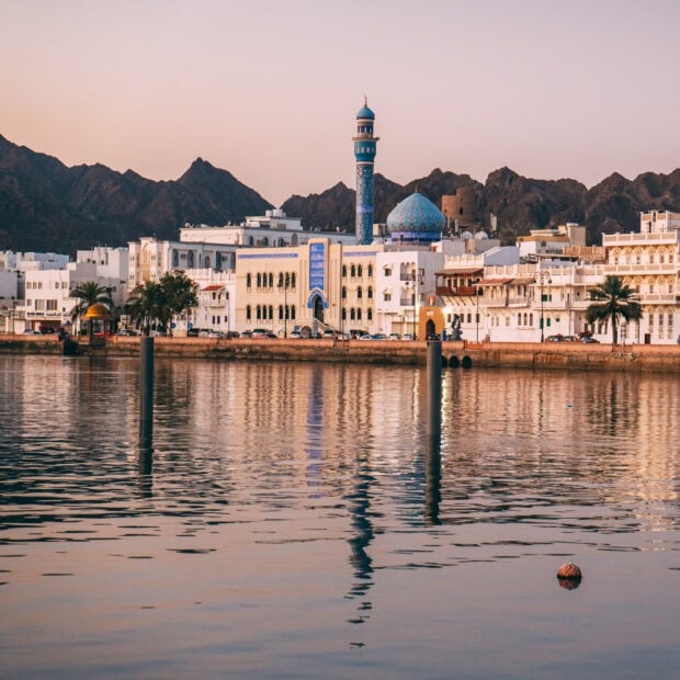 Traditional architecture and mosque tower in Muscat Oman skyline with water reflection