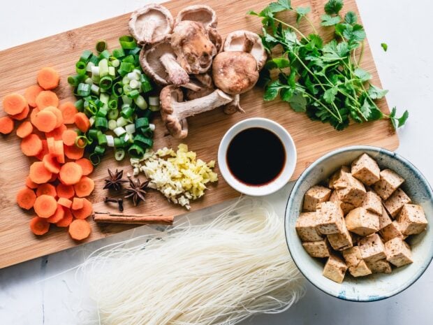 Fresh mushrooms and chopped vegetables prepared on a wooden cutting board for cooking