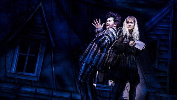 A dramatic musical scene featuring two characters in theatrical costumes on a dark stage set
