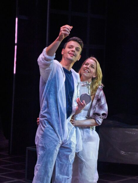 A couple enjoying a musical performance together on stage with a jar in hand