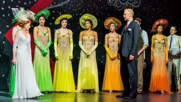 Vintage musical performance with women in colorful dresses and hats on stage in a theatrical scene