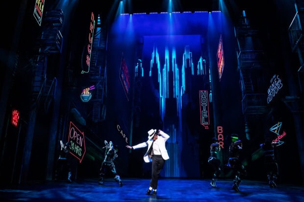 A dance performance featuring a white hat in a lively musical theater scene with neon lights