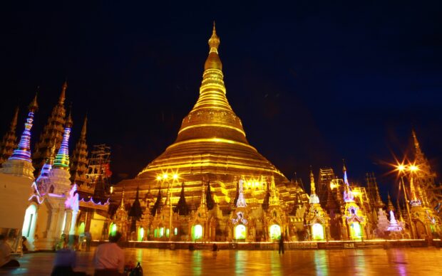 The Shwedagon Pagoda illuminated at night showcasing Myanmar architecture