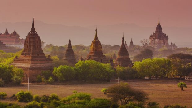 Ancient Myanmar temples surrounded by green trees at sunset in a scenic landscape of Myanmar