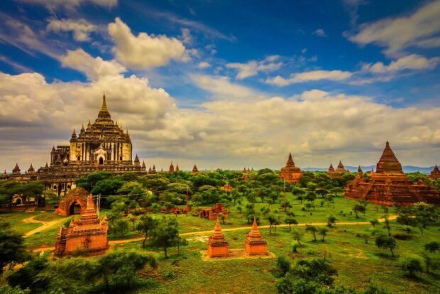 Ancient temples and lush greenery in Myanmar landscape under a cloudy sky