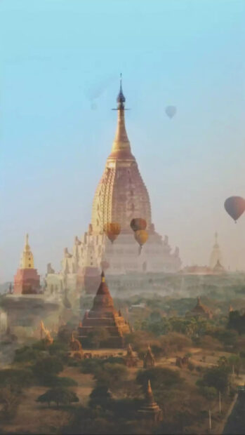 Ancient Myanmar temples with hot air balloons floating in the sky over lush landscape