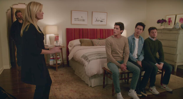 A woman and three men sitting in a bedroom setting from a Nancy Meyers scene