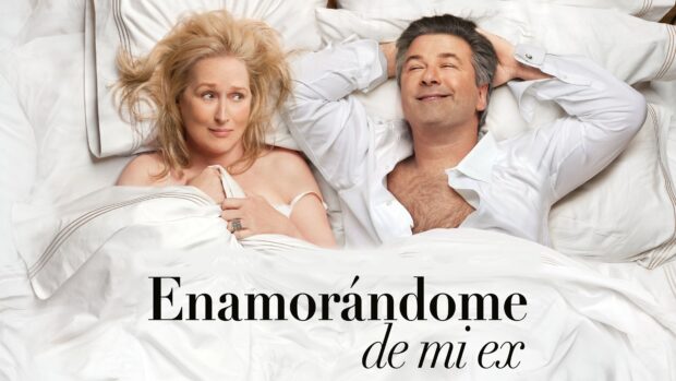 A couple lying in bed with one looking worried and the other smiling in a Nancy Meyers scene