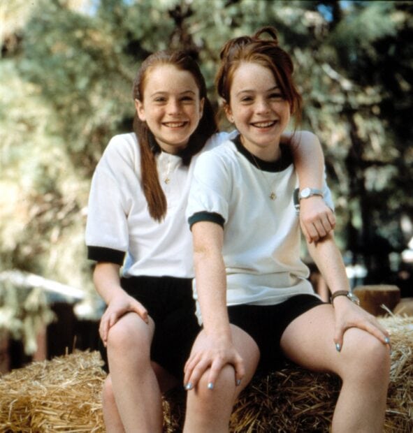 Two happy girls smiling sitting on hay in a Nancy Meyers film scene