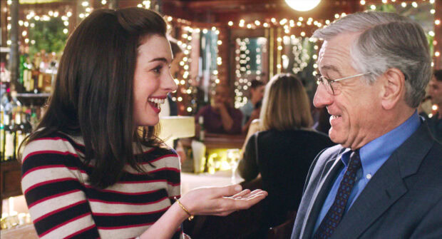 A young woman smiling and talking to an older man in a lively bar setting featuring Nancy Meyers