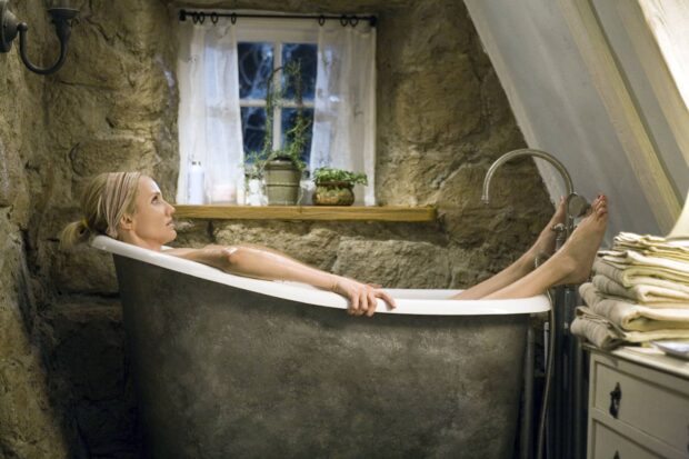 Woman relaxing in bathtub in rustic bathroom with stone walls and window