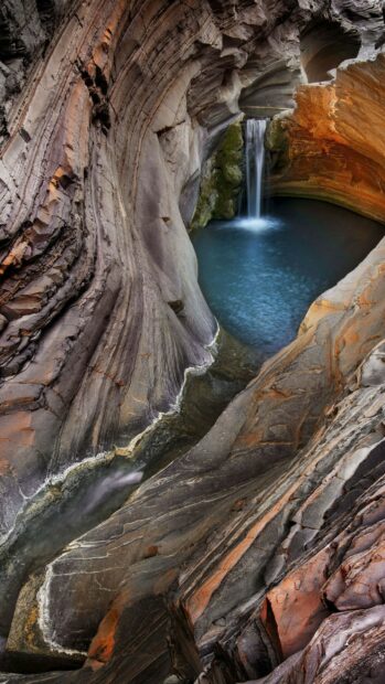 Natural rock formations surrounding a small pool with a waterfall in a canyon National Geographic