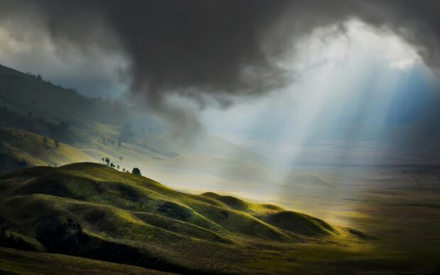 Dramatic landscape of hills with sunlight breaking through clouds in National Geographic scene