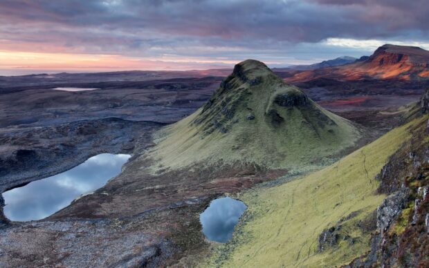 Unique National Geographic landscape featuring mossy hills and reflective water bodies at sunset