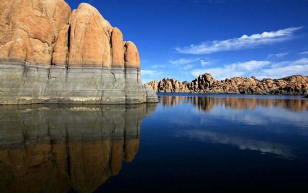 Unique National Geographic rock formations reflecting on calm lake water under a blue sky